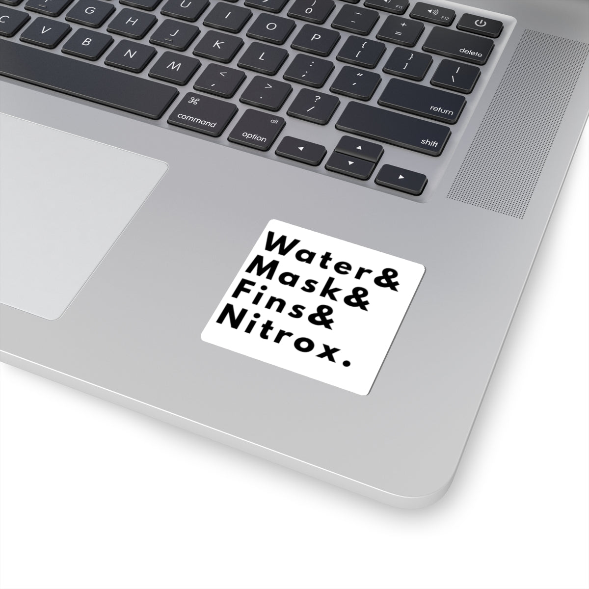 Laptop with a scuba diving inspired sticker listing items related to scuba diving such as water, mask, fins, nitrox on a white background