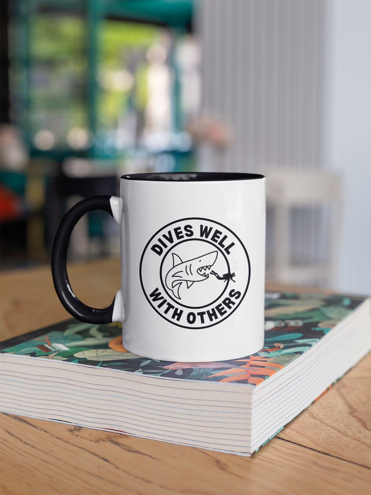 White mug with black handle featuring a shark graphic and text on a stack of books.