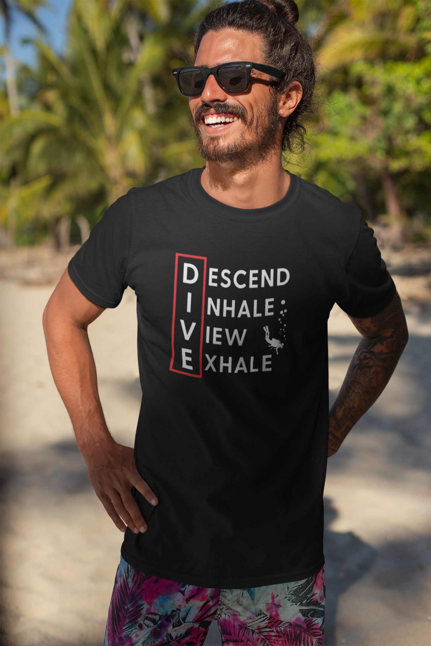 Man wearing a black scuba diving inspired  t-shirt with Descend, Inhale, View, Exhale text on a beach